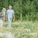 An elderly couple enjoying a peaceful walk in a scenic flower field on a sunny day.